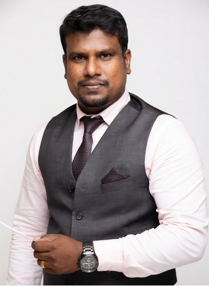 Portrait of Gary Joseph, wearing a grey waistcoat and pink shirt